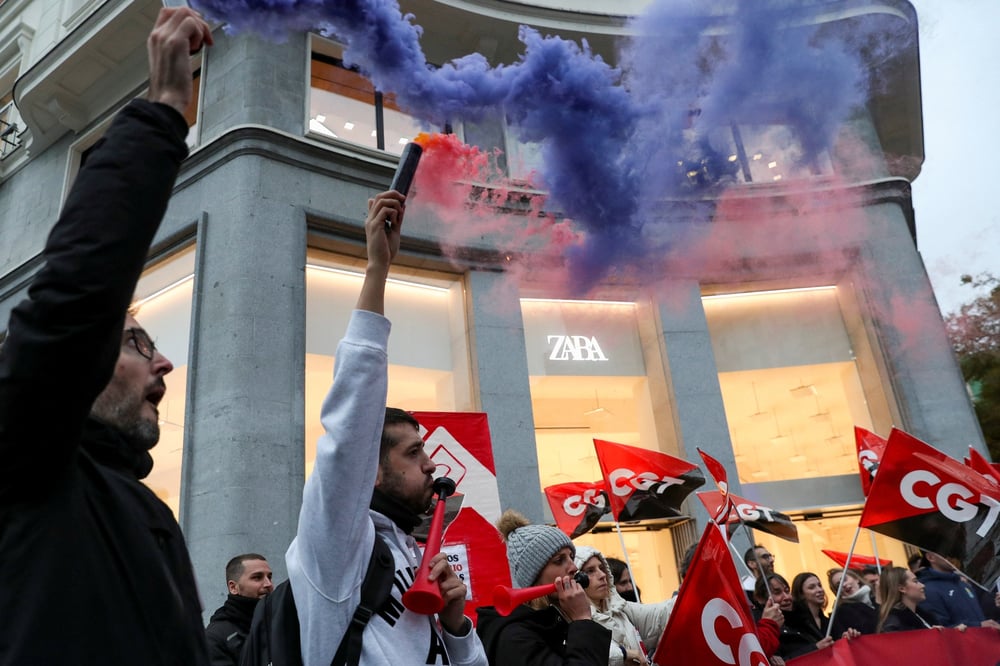 Des personnes tiennent des drapeaux du syndicat espagnol cgt lors d'une manifestation devant un magasin de vetements zara a madrid