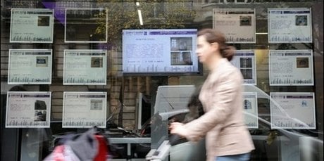 Une personne passe devant une agence immobilière à Paris