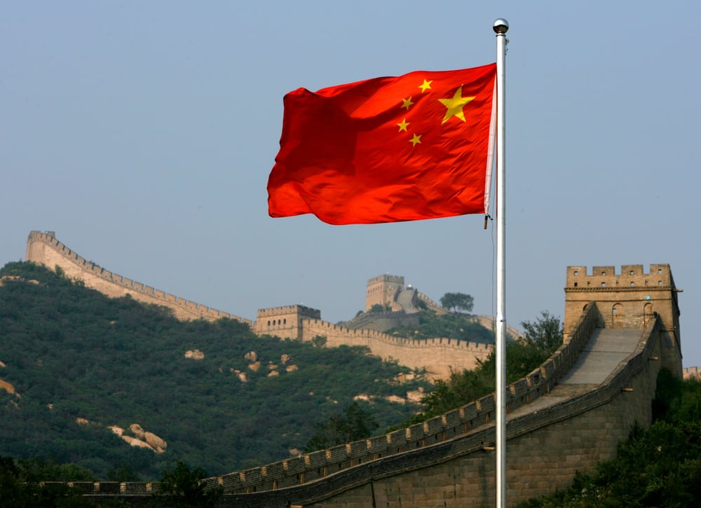 Un drapeau chinois flotte devant la grande muraille de chine, situee au nord de pekin