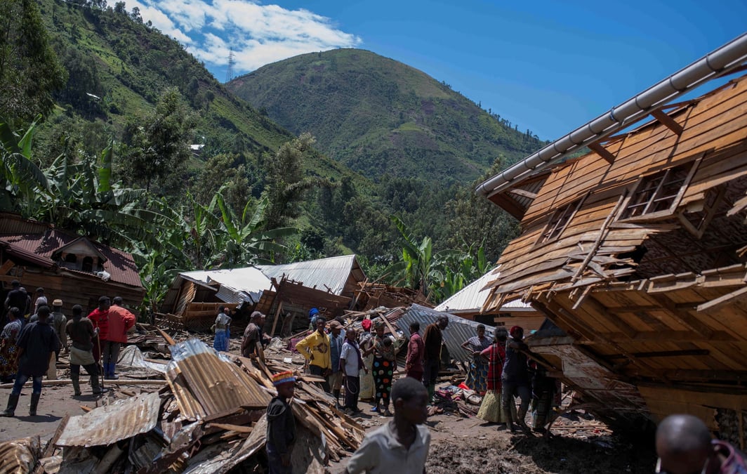 Des civils congolais se rassemblent apres la mort de membres de leur famille a la suite de pluies qui ont detruit des batiments et force des travailleurs humanitaires a rassembler des cadavres recouverts de boue en tas dans le village de nyamukubi