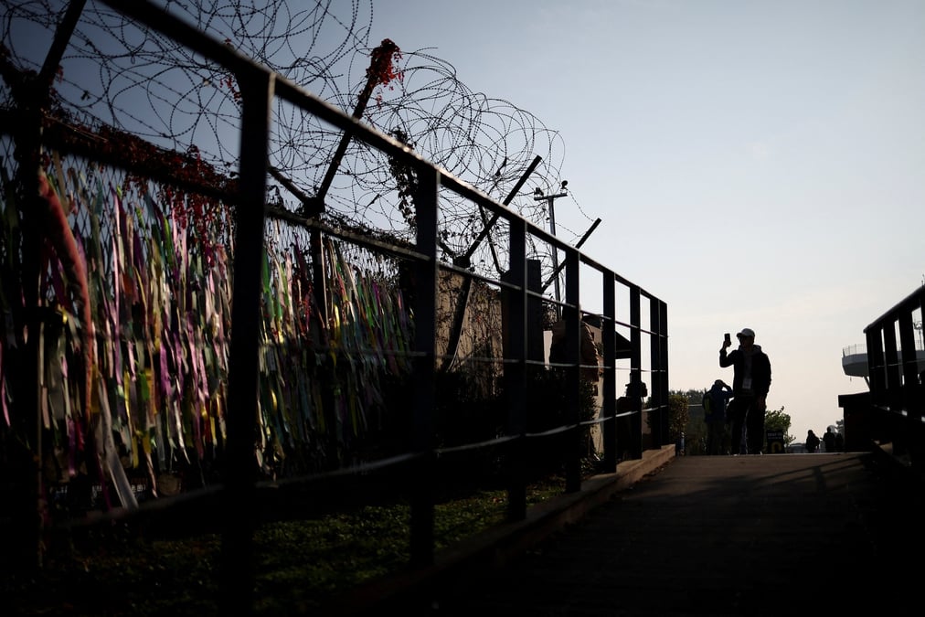 Un homme prend des photographies devant une cloture militaire pres de la zone demilitarisee separant les deux corees