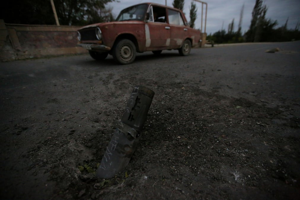 A car drives past the remains of spent ammunition following a recent shelling in tartar