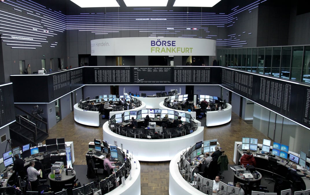Des traders sont photographies a leur bureau devant le tableau du dax a la bourse de francfort