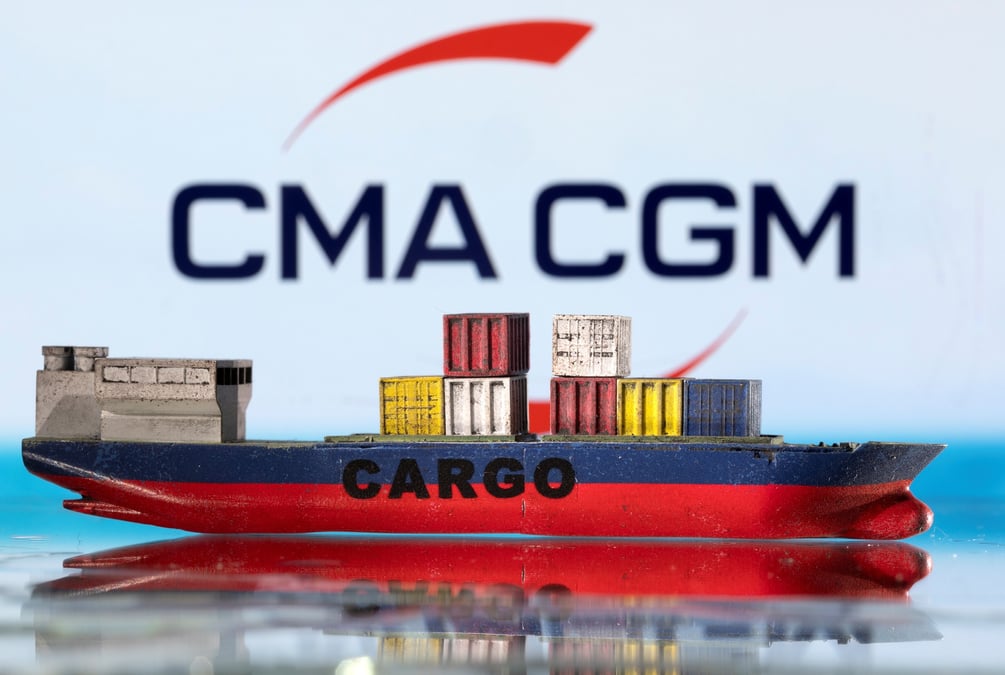 Un modele de bateau cargo est photographie devant le logo de cma cgm.