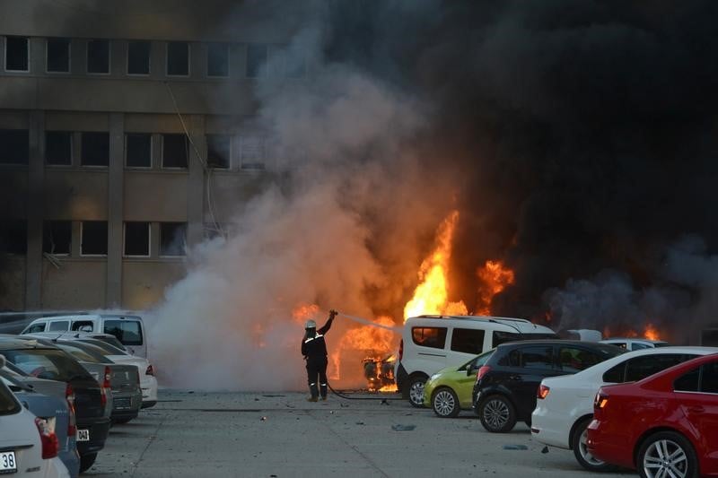 A firefighter tries to extinguish burning vehicles after an explosion outside the governor's office in the southern city of adana