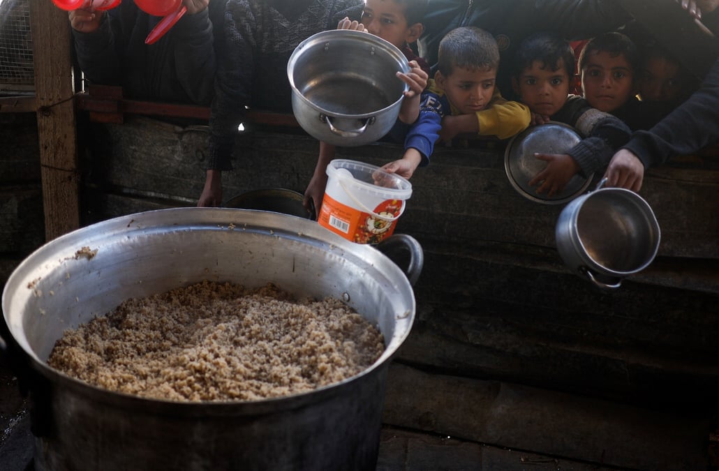 Des enfants palestiniens attendent de recevoir de la nourriture preparee par une cuisine caritative dans un contexte de penurie alimentaire, a rafah