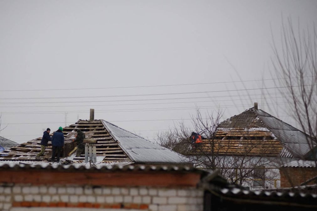 Photo des ouvriers qui reparent le toit d'une maison endommagee du village de petropavlovka, accidentellement bombarde par un avion militaire russe dans l'ouest de la russie