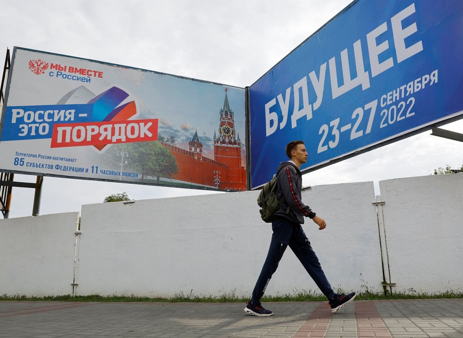Un homme marche devant des panneaux au sujet d'un referendum sur le rattachement a la russie des regions ukrainiennes controlees par la russie, a melitopol, en ukraine