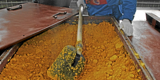A worker rakes uranium oxide after the opening ceremony of the Zarechnoye mine in southern Kazakhstan December 7, 2006. Zarechnoye, a joint venture between Russia and Kazakhstan, produced its first tonne of uranium in Kazakhstan on Thursday in a move that helps Russia secure cheap supplies of the ra