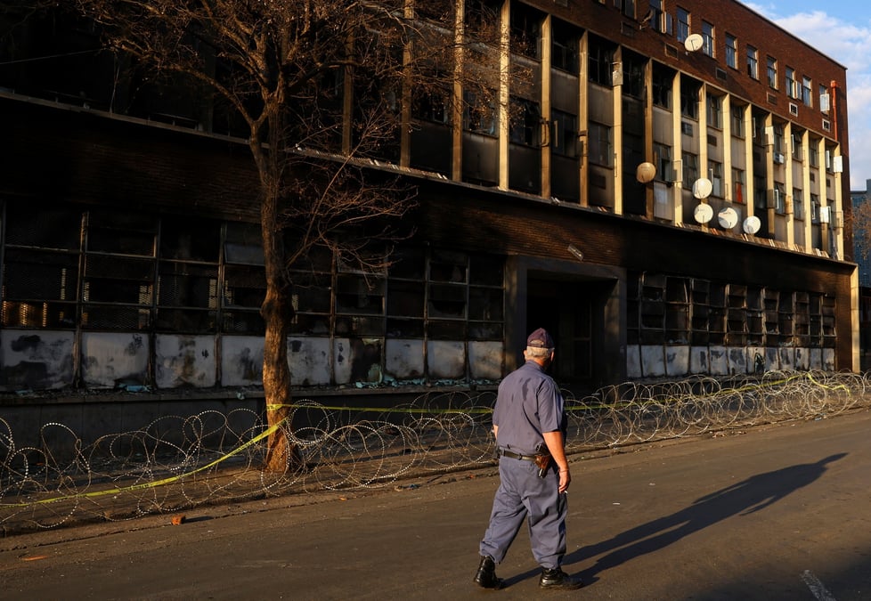 Un policier passe devant l'immeuble ou un incendie meurtrier s'est declare, a johannesburg