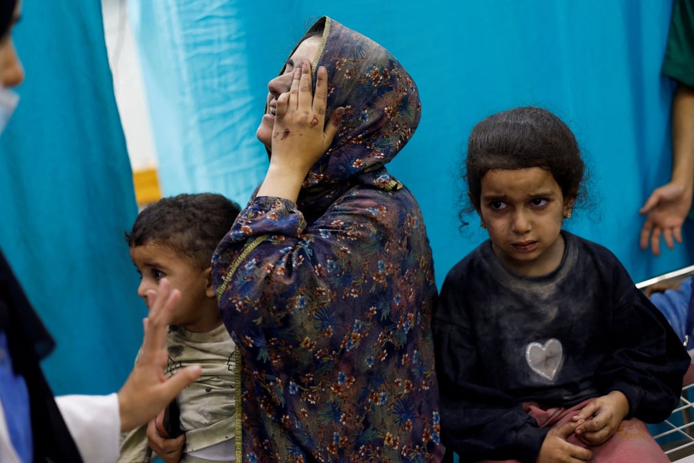 Une femme et des enfants palestiniens, blesses lors de frappes israeliennes, attendent de se faire soigner dans un hopital de gaza