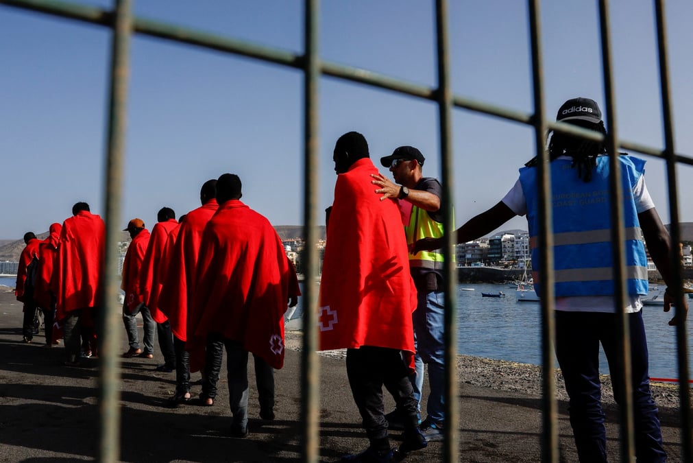 La police frontex accompagne plusieurs migrants vers une tente de la croix-rouge apres leur debarquement d'un navire des garde-cotes espagnols, dans le port d'arguineguin