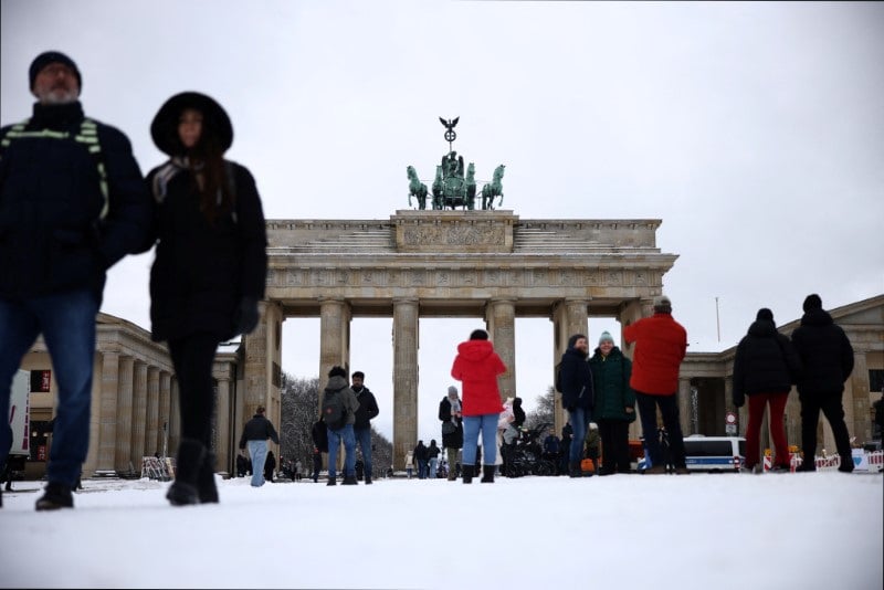 Des passants devant la porte de brandebourg, enneigee, a berlin