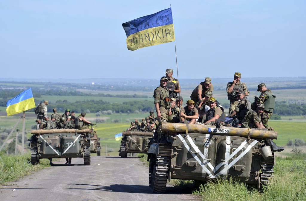 Members of ukrainian armed forces gather on armoured vehicle on roadside near village of vidrodzhennya