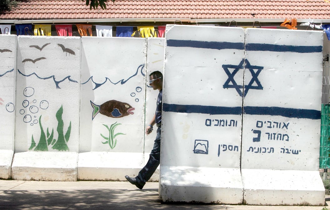 Un colon israelien marche entre des murs de protection en beton dans la colonie de ganim, en cisjordanie