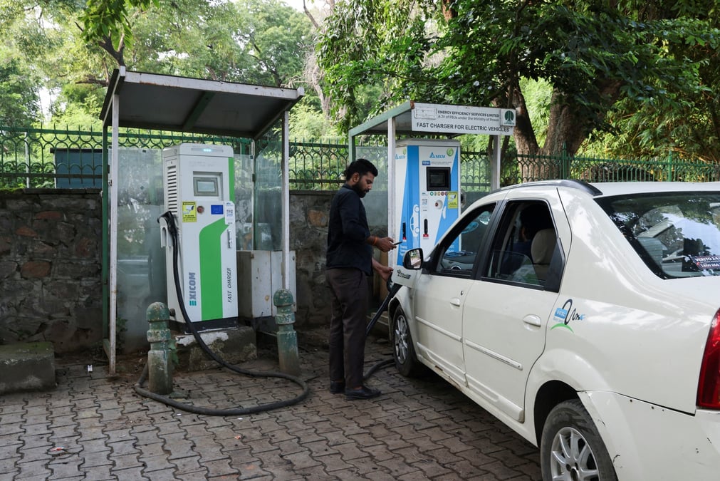 Un homme charge sa voiture electrique a new delhi, en inde
