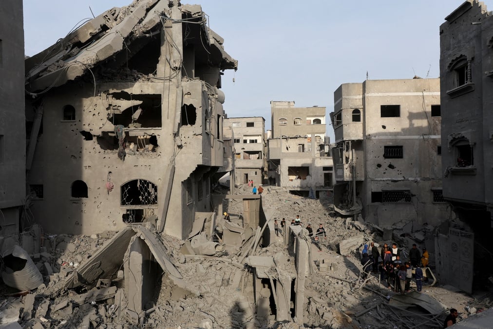 Des palestiniens inspectent les degats sur le site d'une frappe israelienne sur une maison, dans le camp de refugies de nuseirat