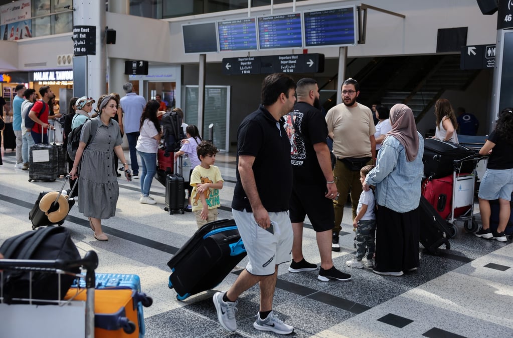 Des personnes se tiennent a cote de leurs bagages a l'aeroport international de beyrouth-rafic hariri, a beyrouth, au liban