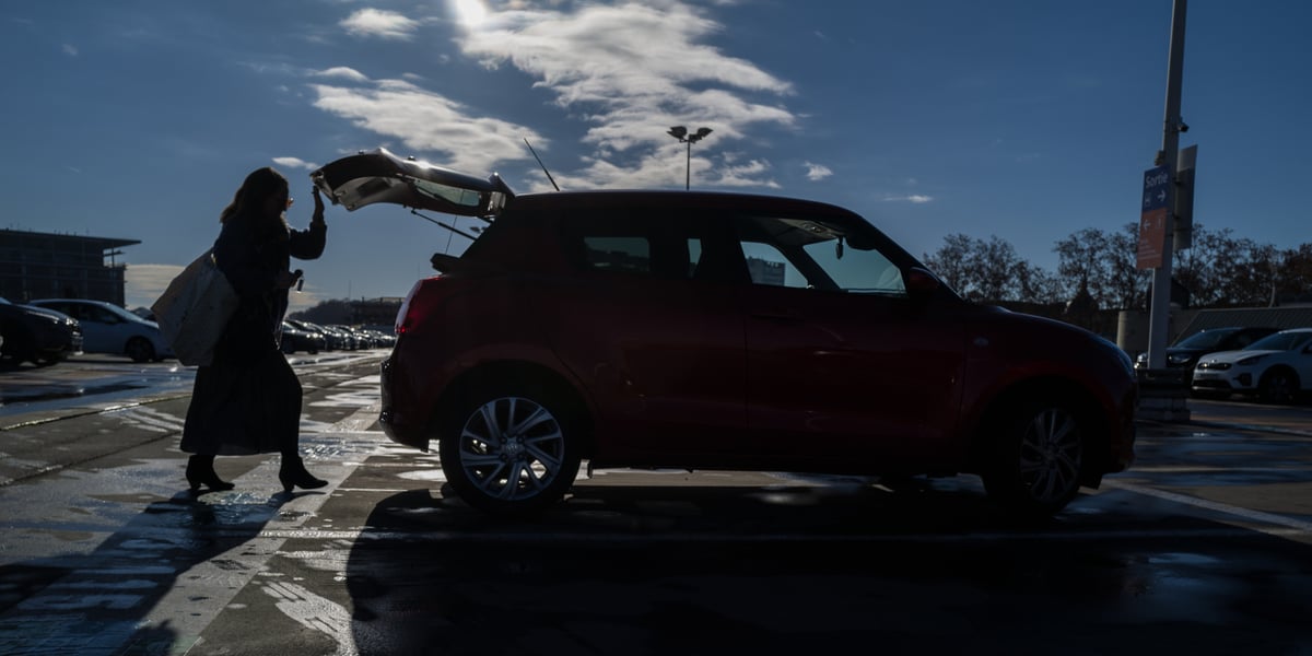 Une femme derrière une voiture de location sur le parking aerien de la gare de Toulouse Matabiau.