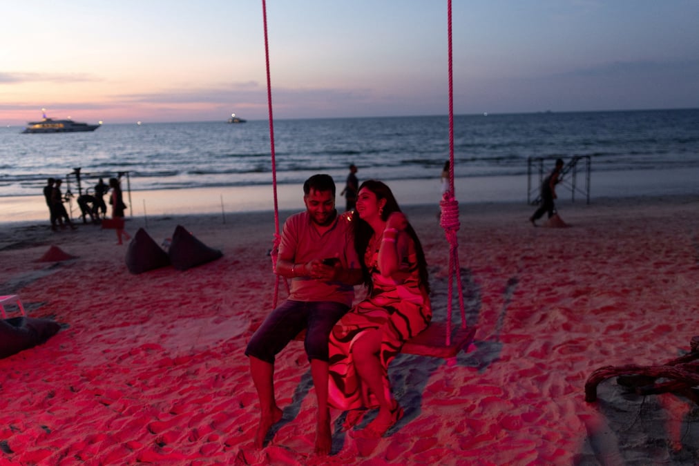 Un couple est assis sur une balancoire au crepuscule sur une plage de phuket