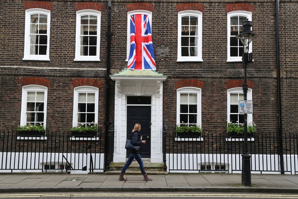 Woman walks past a union jack flag hanging on a house in westminster in london