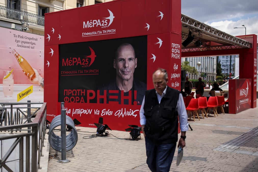 Photo d'un homme qui passe devant le kiosque pre-electoral du parti mera25 a athenes