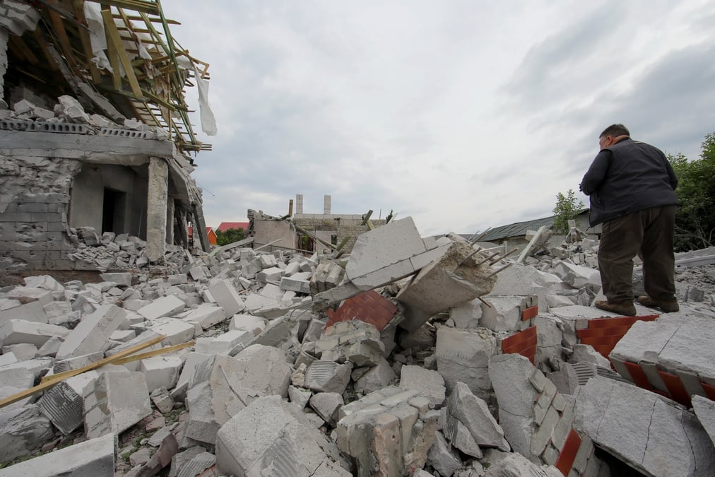 Photo d'un homme qui se tient debout sur les debris d'un batiment fortement endommage par une frappe militaire russe
