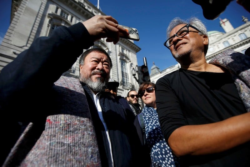 Artists ai wei wei (l) and anish kapoor carry blankets to symbolize the plight of refugees,  as they walk through central london