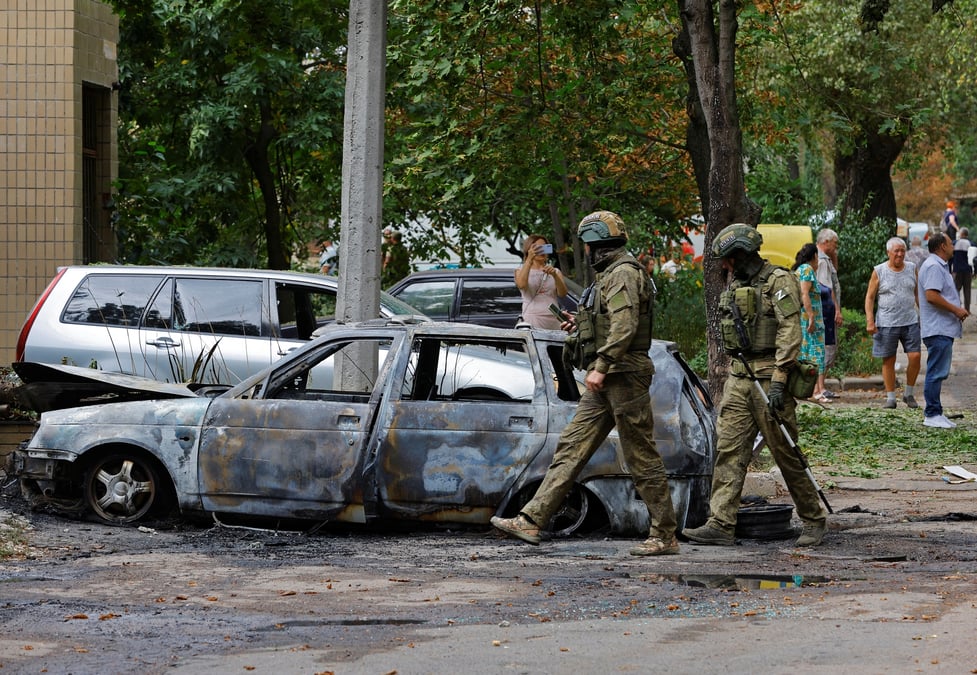 Des soldats russes marchent pres d'une voiture endommagee a donetsk