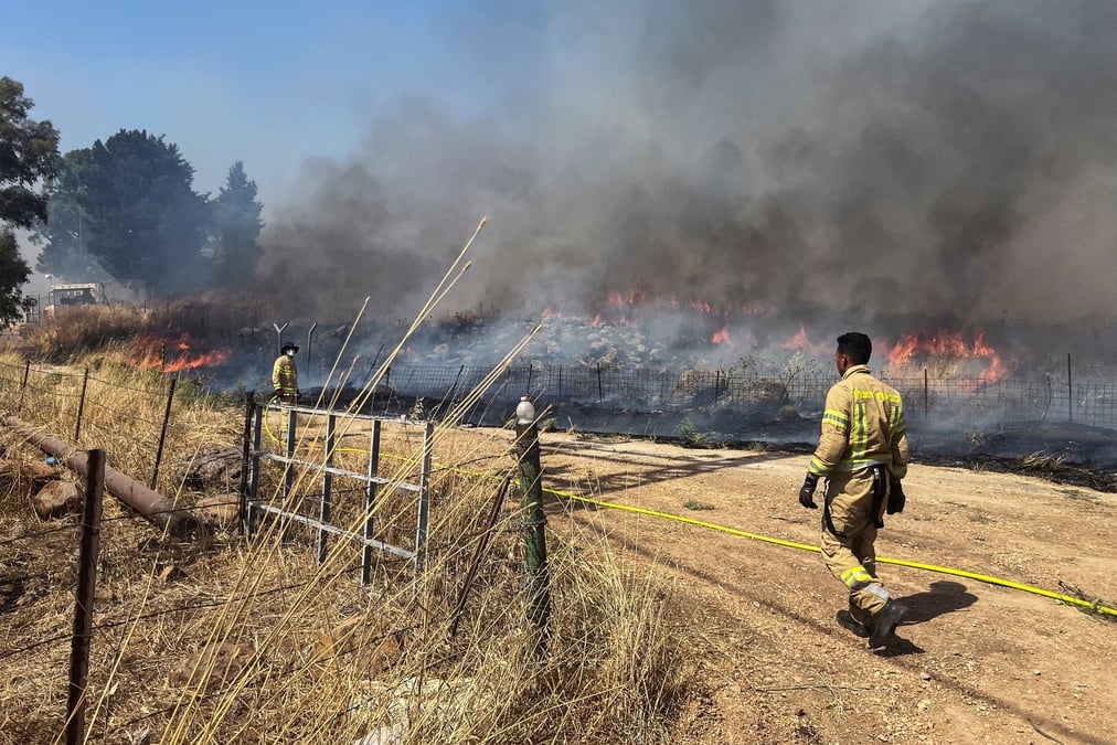 Pompiers israeliens sur le site de tirs de roquettes en provenance du liban, pres de la frontiere du cote israelien