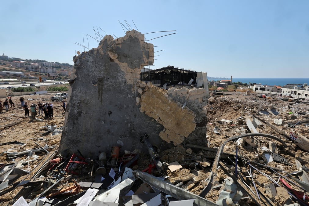 Des personnes inspectent les degats sur le site d'une frappe israelienne qui a touche la ville balneaire libanaise de jiyeh