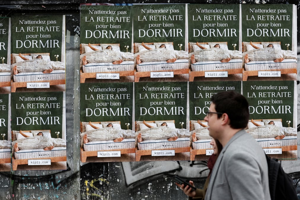 Des gens passent devant des affiches a paris protestant contre le plan de reforme des retraites en france
