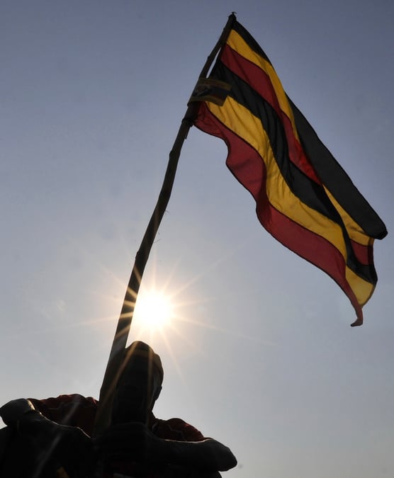 Un homme a cote du drapeau national ougandais a kampala, la capitale du pays
