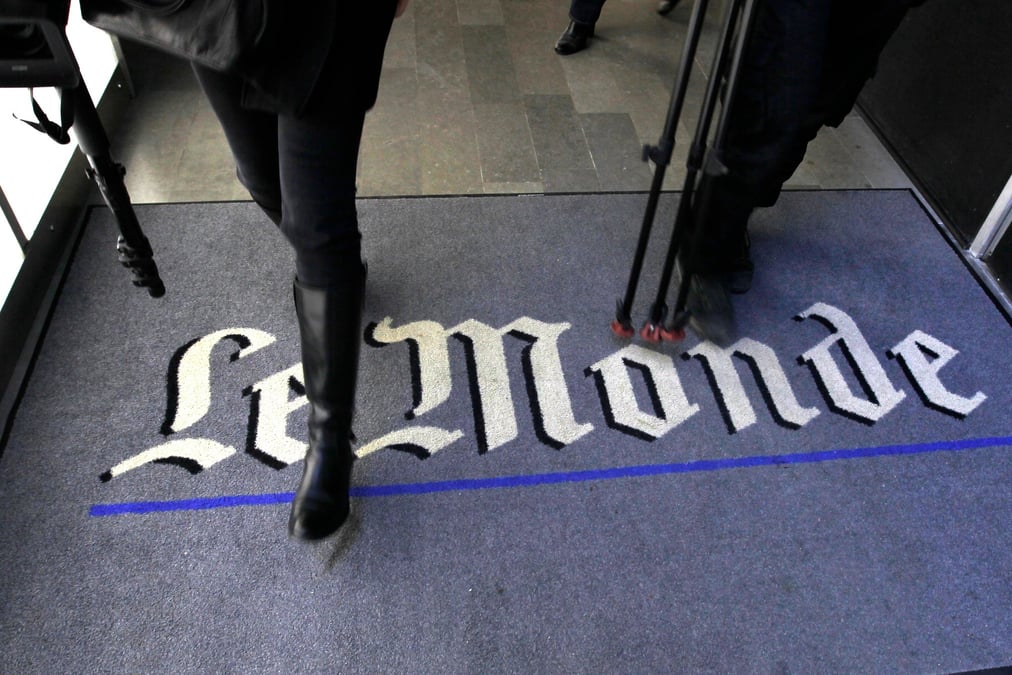 Un journaliste marche sur le logo du quotidien francais le monde dans leurs bureaux a paris