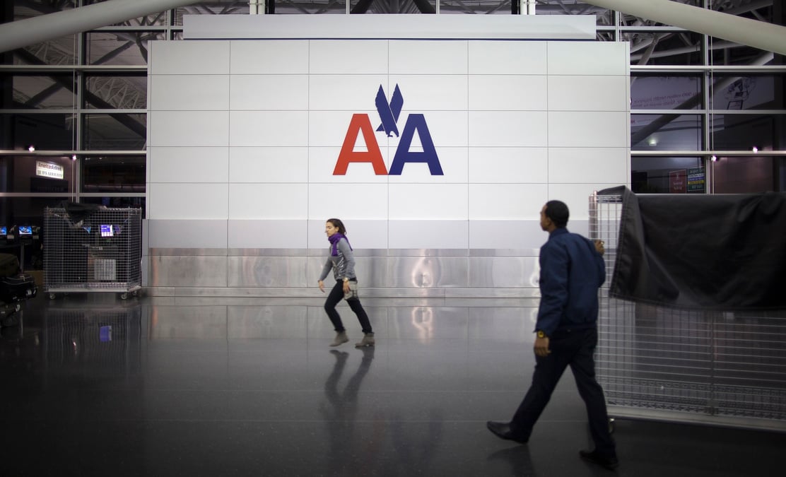 Des personnes passent devant le logo d'american airlines a l'aeroport john f. kennedy (jfk) de new york