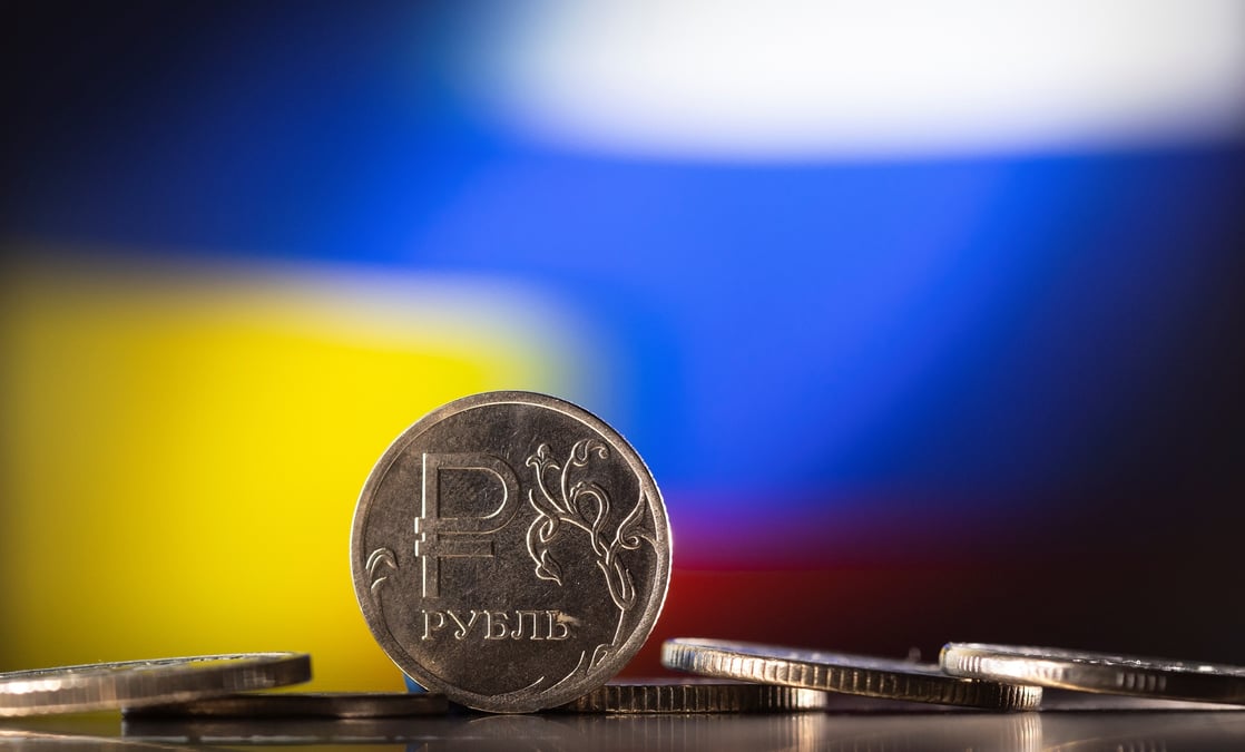 Image d'illustration montre des pieces en rouble russe devant des drapeaux ukrainiens et russes