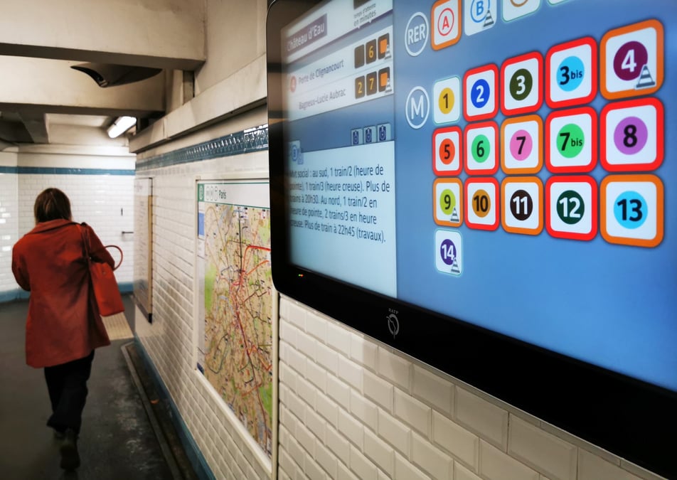 Une femme passe devant un ecran d'information affichant la liste des lignes de metro dont le service est interrompu a paris