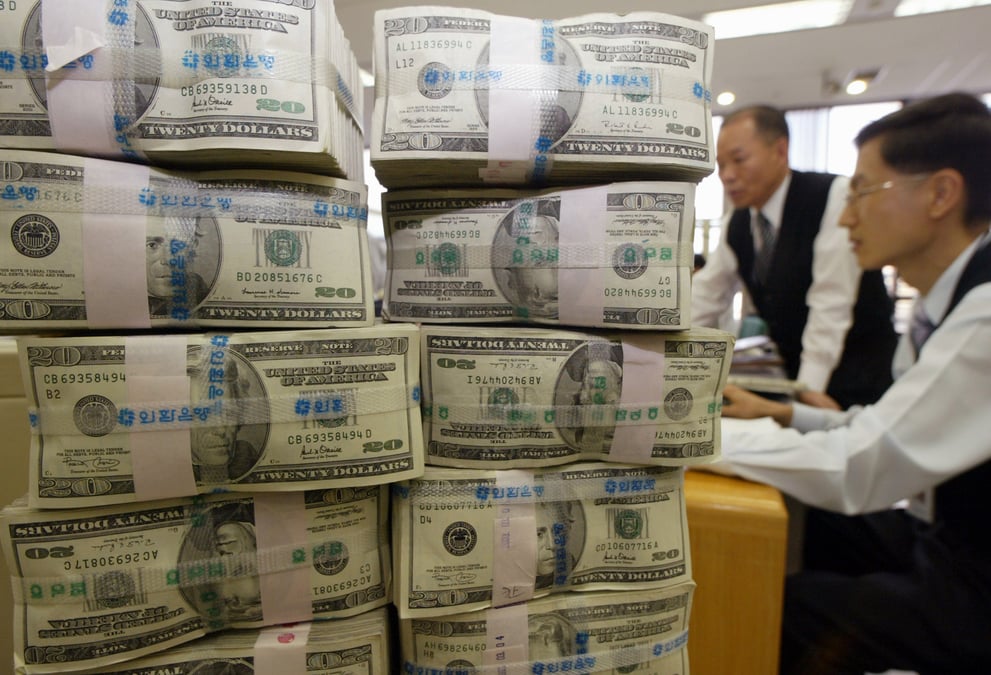 Des employés d'une banque travaillent près d'une pile de billets de monnaie américaine (le dollar) / Argent