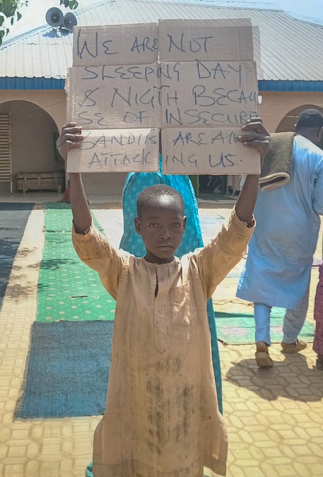 Un garcon tient une pancarte pour protester contre l'enlevement de centaines d'ecoliers par des hommes armes, a kaduna