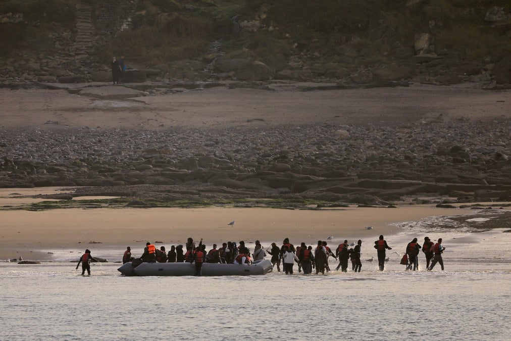 Un groupe de migrants debarque d'un canot pneumatique sur la plage de le portel, dans le nord de la france