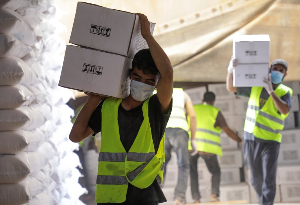 Des travailleurs transportent des boites contenant de l'aide humanitaire pres du poste de bab al-hawa