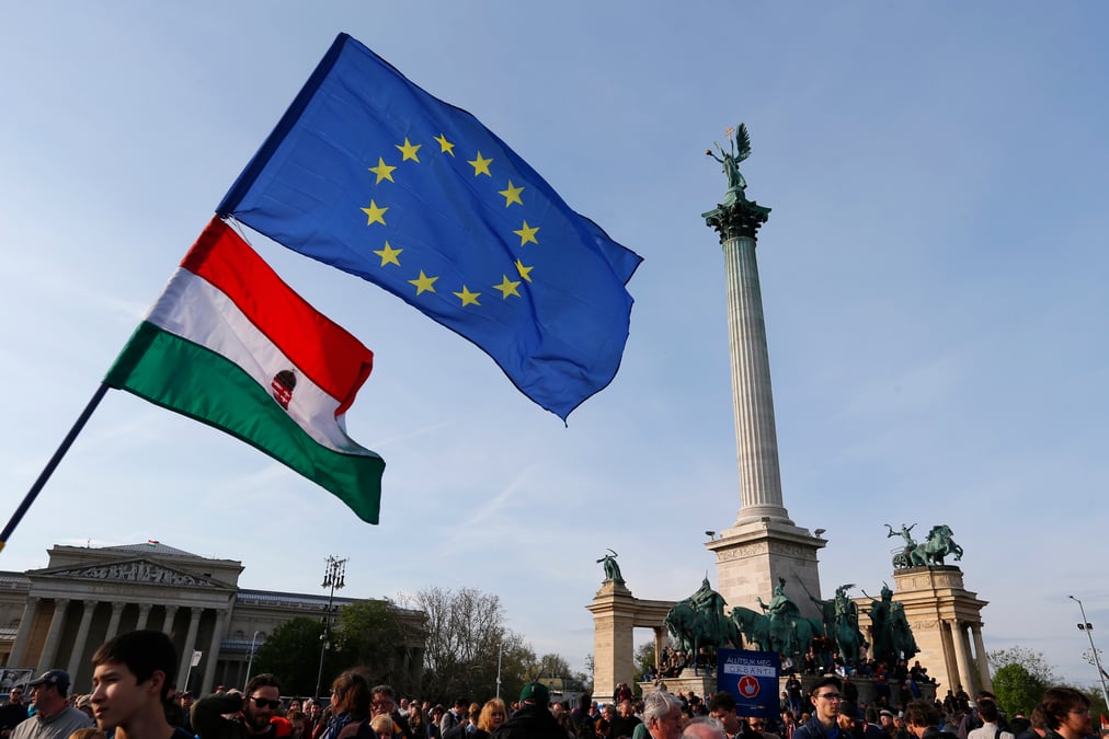 People wave hungarian and european union flags as they protest in heroes’ square against a new law that would undermine central european university in budapest