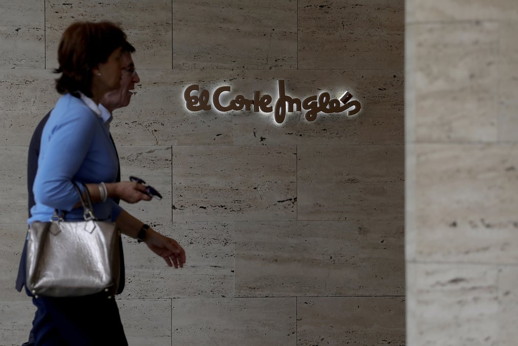 Un couple passe devant le logo d'un grand magasin espagnol el corte ingles