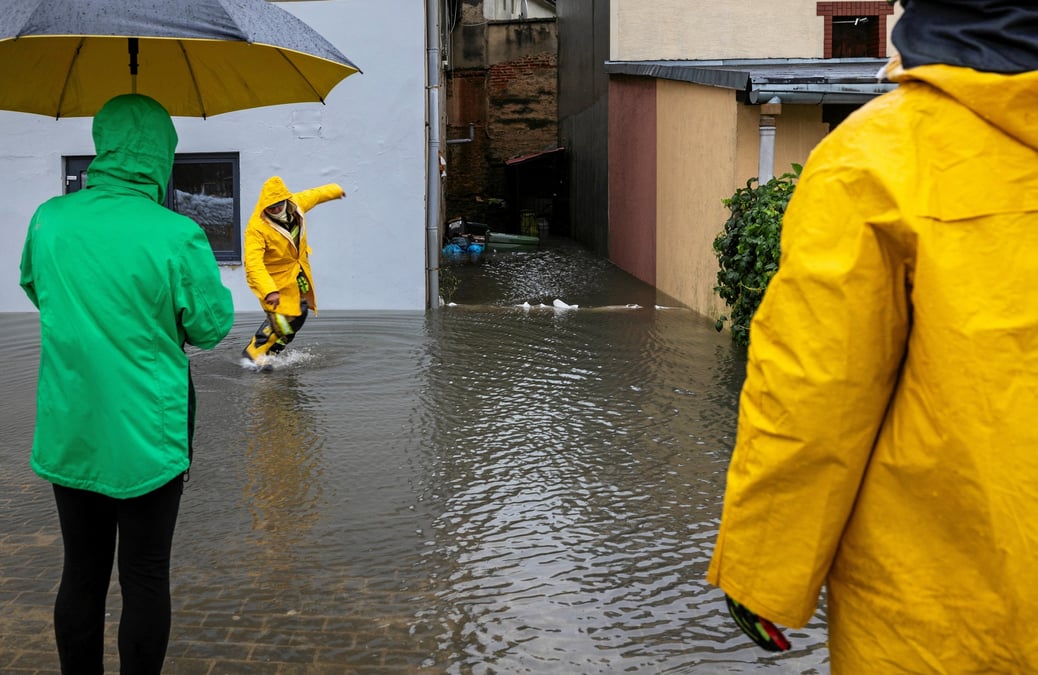 People stand on a flooded street following heavy rainfalls in glucholazy