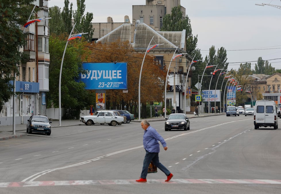 Un homme marche devant des panneaux au sujet d'un referendum sur le rattachement a la russie des regions ukrainiennes controlees par la russie