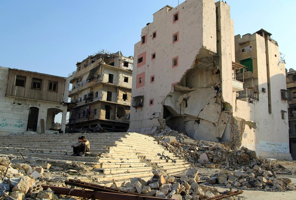 Photo d'archives de garcons assis pres des batiments detruits a alep, en syrie