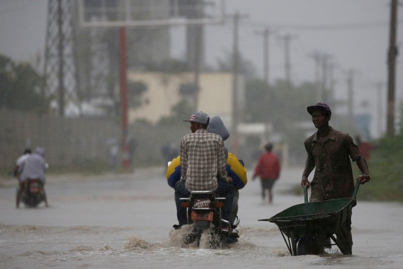 A man pushes a wheelbarrow as he wades across a flooded street while hurricane matthew passes through port-au-prince, haiti
