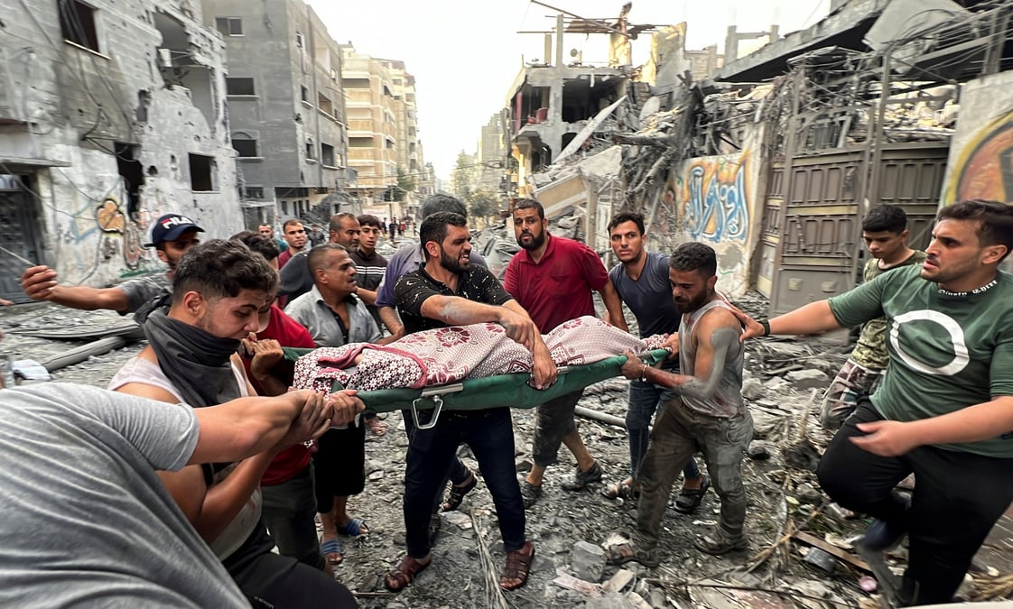 Des palestiniens portent un blesse sur le site de frappes israeliennes sur des maisons, dans la ville de gaza