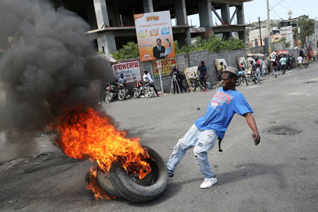 Un homme donne un coup de pied a des pneus en feu lors d'une manifestation antigouvernementale a port-au-prince, en haiti