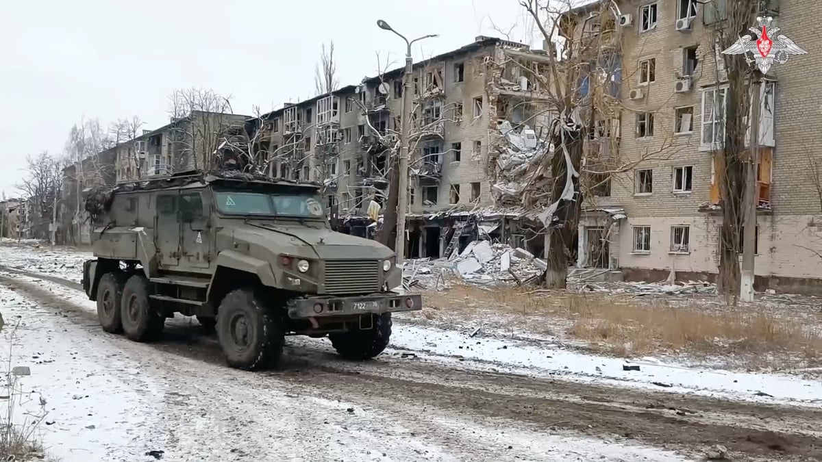 Un vehicule militaire russe passe devant des batiments residentiels endommages dans la ville d'avdiivka